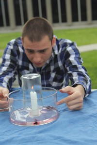 Athanasios Klovtsiniotis, 21, demonstrates a “candle trick” at the Chemistry Club booth on March 11 during Club Rush. As the glass beaker smothers the flame out the water rises into the glass. (Jessica Soto/Citrus College Clarion)