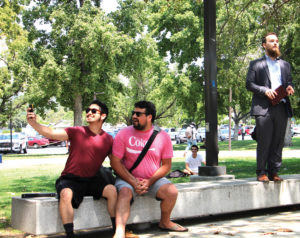 Students and best friends Jacob Gomez and Ryan Grosjean ask preacher Sebastian Bryan to take a selfie with them during his open air preaching Aug. 25 in the Campus Center Mall. Bryan was speaking out against homosexuality when Gomez and Grosjean held hands and sat down next to him in protest. (Evan Solano/Clarion)